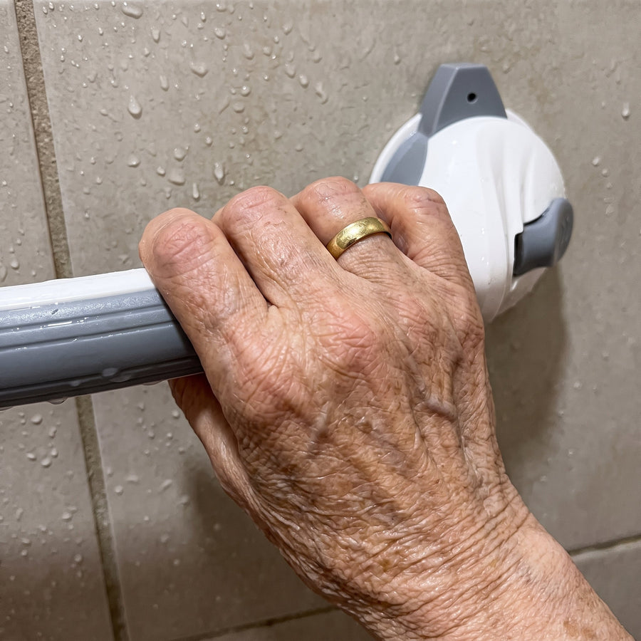 Mano de persona mayor agarrando firmemente la barra de la ducha